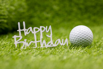 Happy Birthday sign with golf ball are on green grass