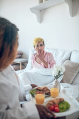 Woman in pleasant surprise and girlfriend with breakfast