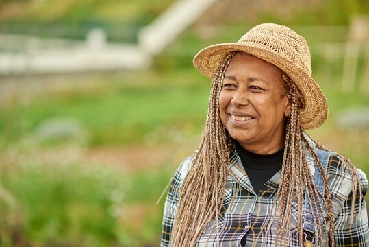 Smiling ethnic farmer in straw hat on plantation