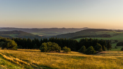 Naklejka na ściany i meble Golden hour at highest point of Rhoen Mountains Wasserkuppe with hilly landscape, Germany
