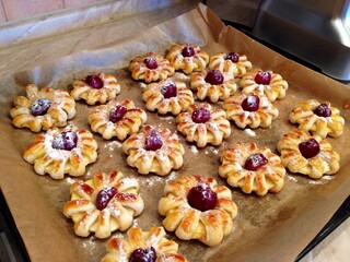 Pineapple cherry puff pastry dessert. Baked fruit (pineapple cherry) puff pastry cake on paper. Baking sheet with puff pastry cookie on cooking paper. Pineapple cherry puff pastry on pan background