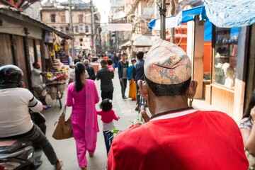 Rikshaw driver on a busy street wearing red shirt.