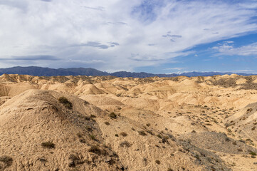 Fototapeta na wymiar dried sand dunes against the backdrop of mountains and blue sky