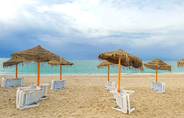 white plastic sun loungers, sun umbrellas on the beach.