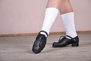 Close-up of female legs in black leather shoes dancing national Irish dances.