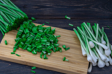 fresh chopped green onions on a cutting board on a dark background