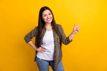 Photo of impressed charming young woman wear khaki outfit pointing finger empty space isolated yellow color background