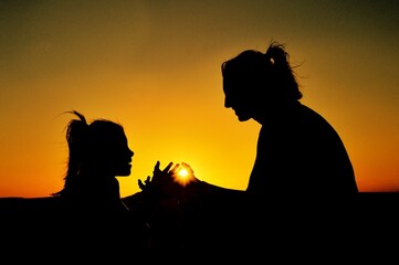 Silhouette of a mother and her child holding together the sunset