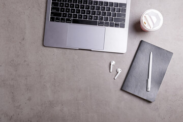Cropped shot of minimalistic workspace. Tabletop of concrete textured desk with metallic grey laptop. Workplace of a developer concept. Background, copy space for text, flat lay, close up, top view.
