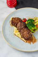 Grilled beef tenderloin steak on a ceramic plate with butter and thyme. Filet Mignon recipe with vegetables