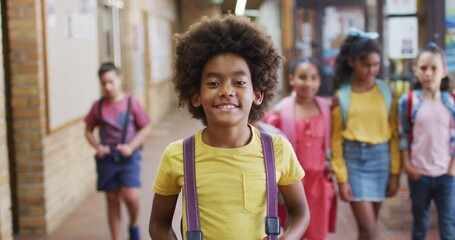 Portrait of happy african american schoolboy standing in corridor looking at camera - Powered by Adobe