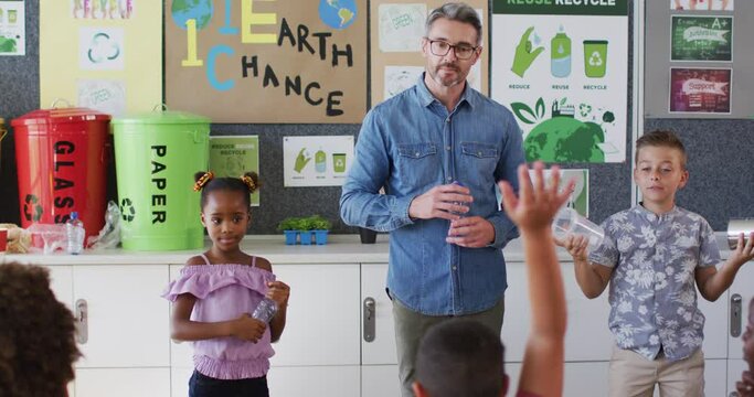 Diverse teacher and schoolchildren standing in classroom learning about recycling trash