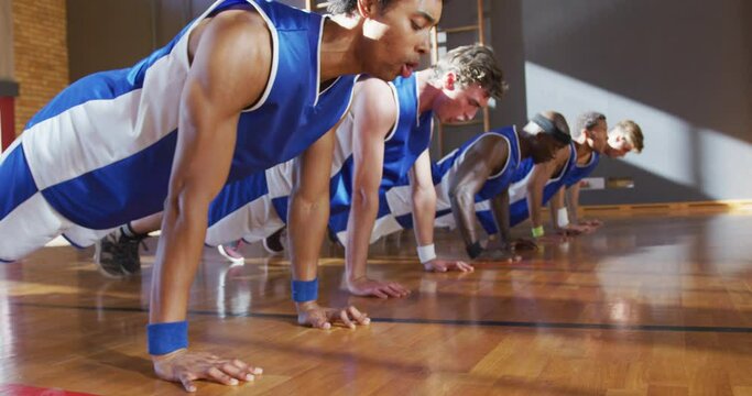 Diverse male basketball team wearing blue sportswear and doing push ups