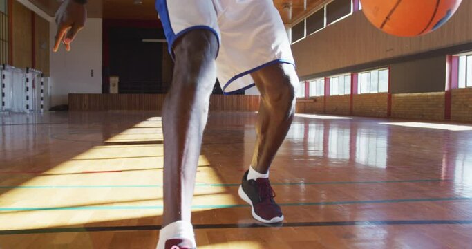 African american male basketball player practicing dribbling ball