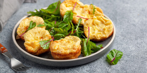 Egg muffins ( bites) and leaves of chard and arugula in a plate on a gray background