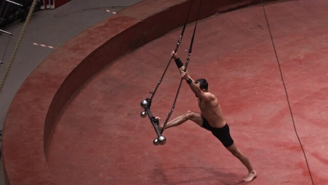 An acrobatic man about to do a show on the flying construction - swinging the construction to the side