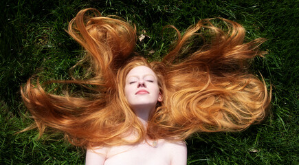 Top view to beautiful portrait of young sexy redhead woman, lying contend in the spring, summer...