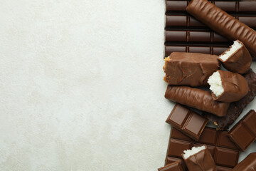 Different tasty candy bars on white textured background