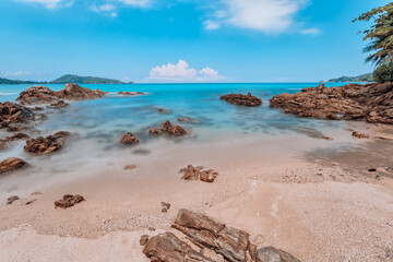 Beautiful rocky sea in the summer of Patong Beach, Phuket, Thailand, on a sunny day overlooking the horizon and blue sky. with the turquoise sea Taken with the long shutter technique.