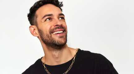Closeup portrait of a smiling man looks at one side, dressed in black t-shirt with copy space for your advertising text, isolated over grey studio background.