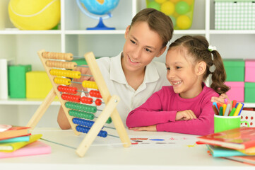 Fototapeta premium Boy and girl sitting at table and counting on abacus