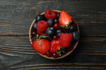 Bowl with berry mix on wooden background