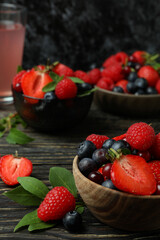 Bowls with berry mix and juice on wooden table