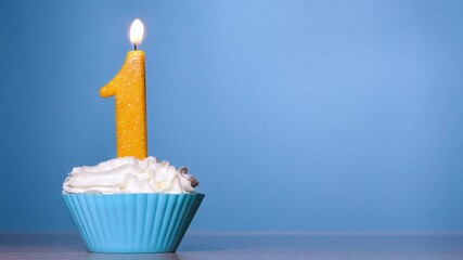 Blow out the candle on the cake. Birthday Cake With Burning Colorful Candle number one on Pastel Blue Background. 120 FPS. Slow motion anniversary banner with copy space.