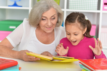 Fototapeta na wymiar Girl doing homework with her grandmother at home