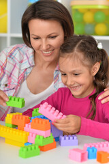 Cute little girl playing with colorful clay blocks at home