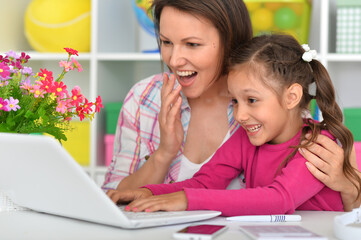 Porait of mother and daughter using laptop