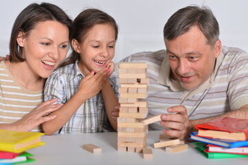 Happy family sitting at table and playing with wooden blocks