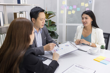 Motivated middle-aged Asian businessman and two young businesswomen happily exchanged ideas for business plans, enjoying working together at the office. leadership workplace.