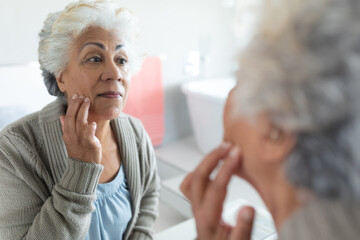 Mixed race senior woman looking at her reflection in mirror