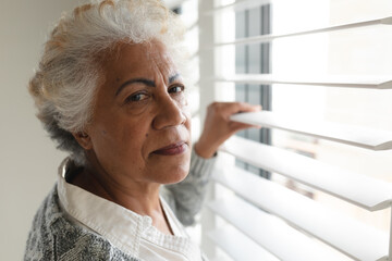 Portrait of mixed race senior woman looking at camera next to window