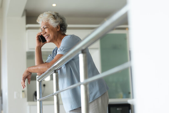 Mixed race senior woman leaning on the handrail talking on smartphone