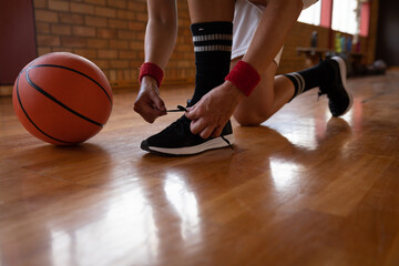 Caucasian female basketball player tying shoes and wearing sportswear