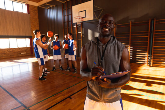 Portrait Of African American Male Basketball Coach With Team In Background