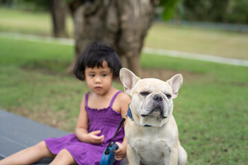 Cute little girl sitting outdoor with adorable French bulldog.