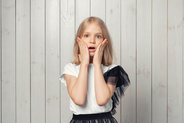 Portrait of startled blonde teen girl raising hands and gasping worried, staring shocked and confused at camera