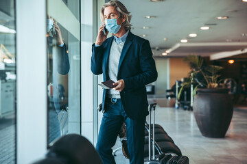 Business traveler waiting for his flight at airport lounge during pandemic