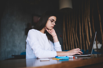 Fototapeta na wymiar Focused woman browsing laptop in workplace