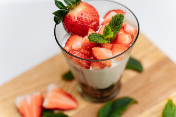 Gentle dessert with fresh berries, mint and cinnamon in a glass cup on the table