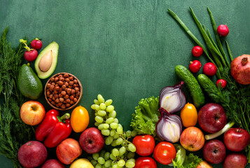 Frame of assorted fresh vegetables and fruits on green table. Food frame on green background with copy space.