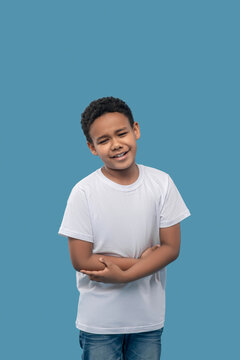 Sad dark skinned boy holding stomach with hands