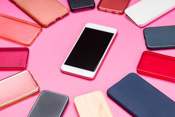 Choice of multicolored plastic back covers for mobile phones on pink background with a smart phone on the side