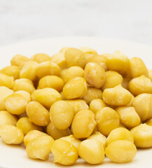 Close up raw macadamia seeds on plate on stone background with copy space