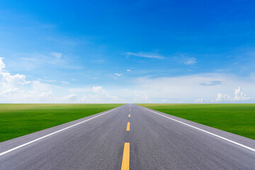 long road into grass field and blue sky
