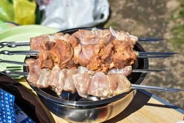 juicy shish barbecue from fresh meat on skewers for cooking on grill. Departure for nature, picnic season. prepared appetizer for frying over fire. Raw meat is strung on BBQ. shashlik is ready to cook