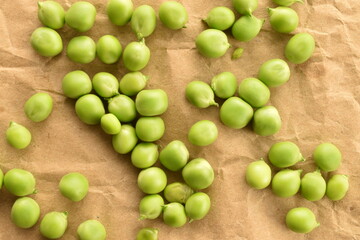 Several ripe organic, green peas on craft paper, close-up, top view.